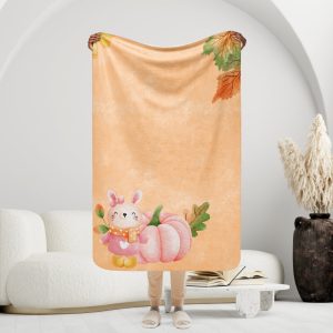 Manta mullida con conejita y calabaza en fondo color salmón con hojas de otoño